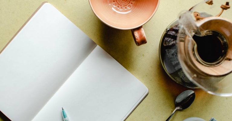 Spaces - A Blank Notebook Beside Empty Cup and Coffee Maker