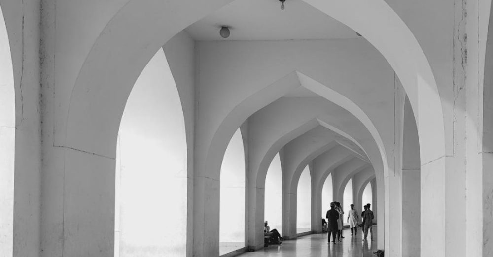 Corridors - A black and white photo of people walking through an arched hallway